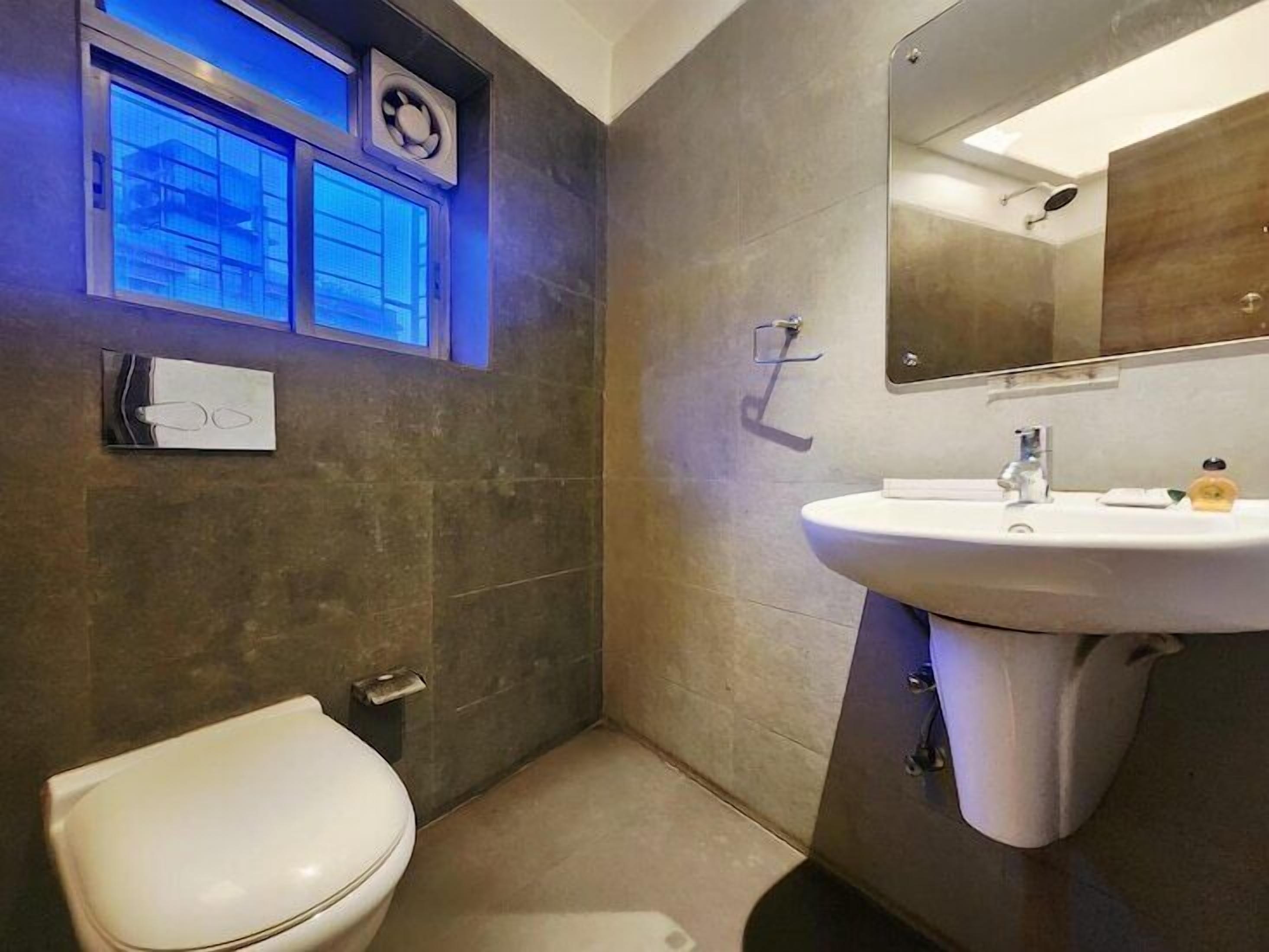 A modern bathroom with a toilet, sink, and mirror.