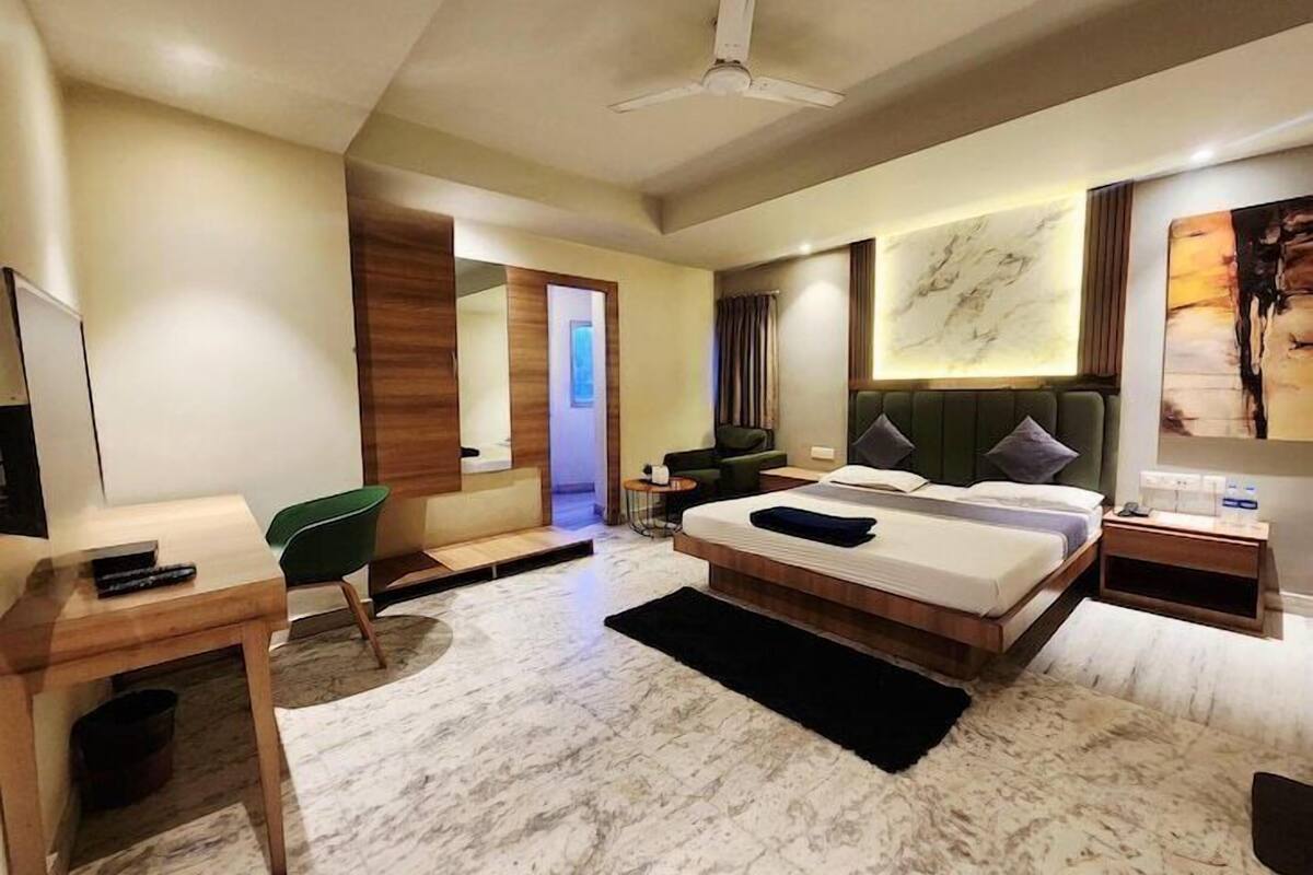 Quarto de hotel moderno com uma cama grande, uma escrivaninha, uma cadeira e um ventilador de teto.