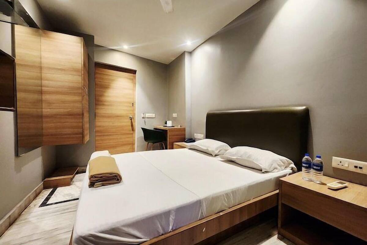 Quarto de hotel moderno com uma cama grande, uma escrivaninha, uma cadeira e um guarda-roupa.