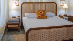 A neatly arranged bedroom with a rattan bed, a wooden nightstand, a floor lamp, and a ceiling fan. - Tranquil Villa in Colombo Suburbs (Moratuwa)