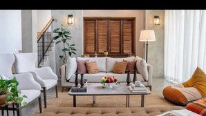 A modern living room with a sofa set, a coffee table with decorative items, and a staircase. - Tranquil Villa in Colombo Suburbs (Moratuwa)