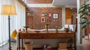 A modern living room with a brick wall, a wooden console table, and a large floor lamp. - Tranquil Villa in Colombo Suburbs (Moratuwa)