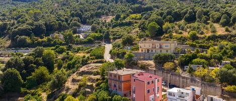 Un barrio residencial en una ladera con edificios, una carretera y vegetación densa.