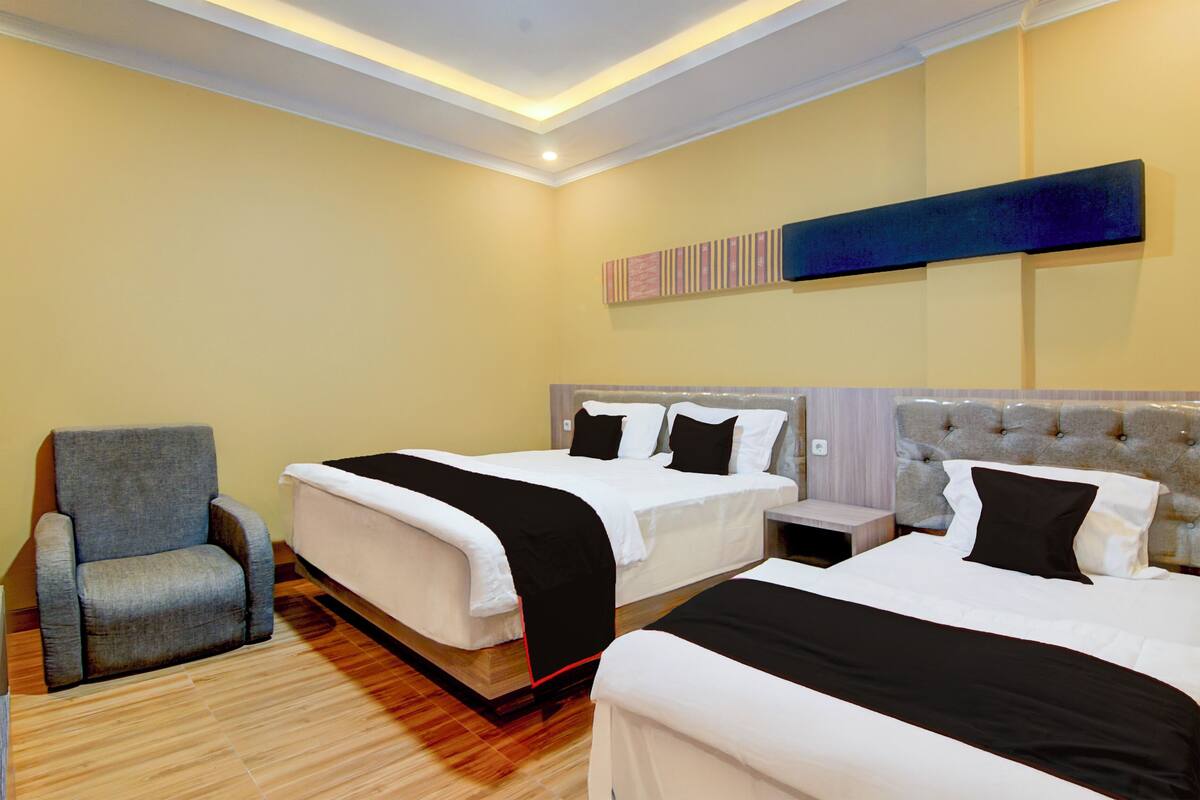 Habitación de hotel con dos camas, una silla y una mesita.