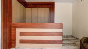 A reception desk with a wooden finish and a marble-tiled floor. - Collection O 94762 Starlight  (Pekanbaru)