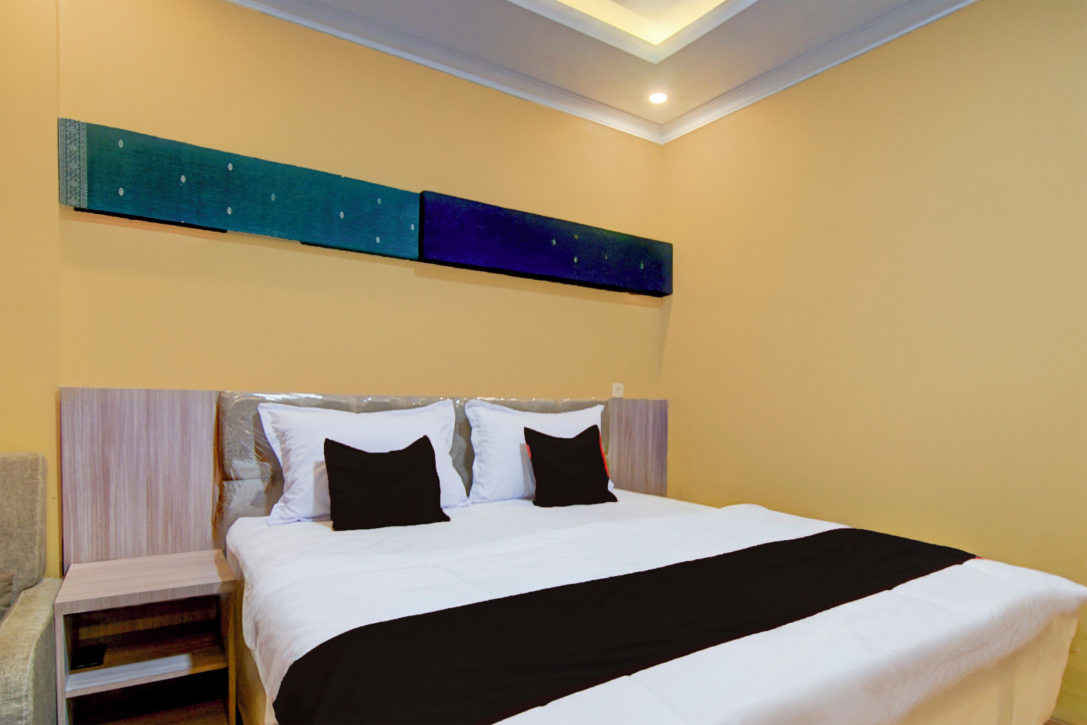 Una habitación de hotel con una cama, una mesita de noche y una obra de arte colgada en la pared.