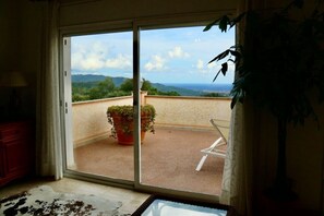 A room with a sliding glass door leading to a balcony with a potted plant and a chair. - Villa Dream View, private pool & spectacular views of the Mediterranean (Lloret Blau)