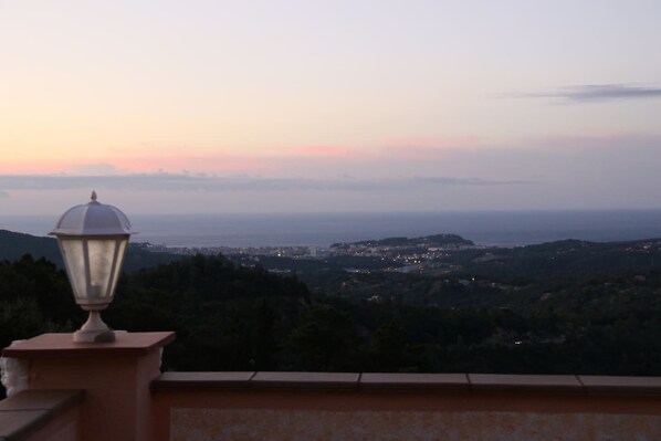 A balcony with a view of a coastal town at dusk.