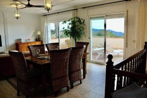 A dining area with wicker chairs, a wooden table, a ceiling fan, and a view of a balcony with outdoor furniture. - Villa Dream View, private pool & spectacular views of the Mediterranean (Lloret Blau)