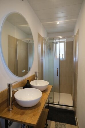 Un baño moderno con dos lavamanos, un espejo grande y una cabina de ducha de vidrio.