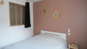 Ein Schlafzimmer mit einem Bett, einem Fenster mit Vorhang und zwei an der Wand befestigten Spiegeln.