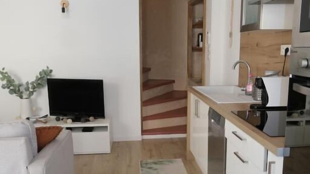 Ein kompakter Wohnbereich mit Küchenzeile, Essbereich und Fernseher.
