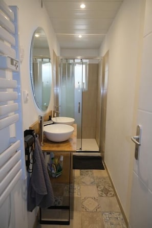 A bathroom with a white sink, a mirror, and a shower.