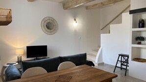 Un soggiorno moderno con un tavolo da pranzo in legno, un divano, una TV e una scala che conduce a un livello superiore.