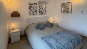 Una camera da letto con un letto, due comodini, lampade a parete e opere d'arte astratte alle pareti.