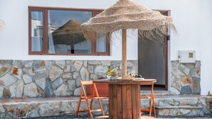 A wooden table with chairs and a woven umbrella outside a building with stone walls and windows. - Holiday Home '2' with Wi-Fi and Air Conditioning (El Golfo)