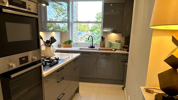 Una cocina moderna con horno integrado, un lavabo y un ventanal que proporciona luz natural.