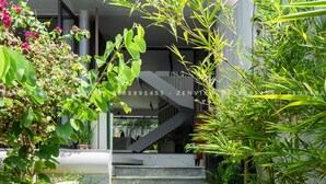 Un escalier menant à un bâtiment moderne au design architectural unique, entouré d’une végétation luxuriante et de plantes.
