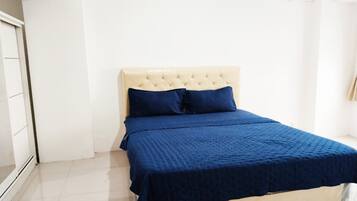 A bedroom with a bed, a white headboard, and a blue bedspread.