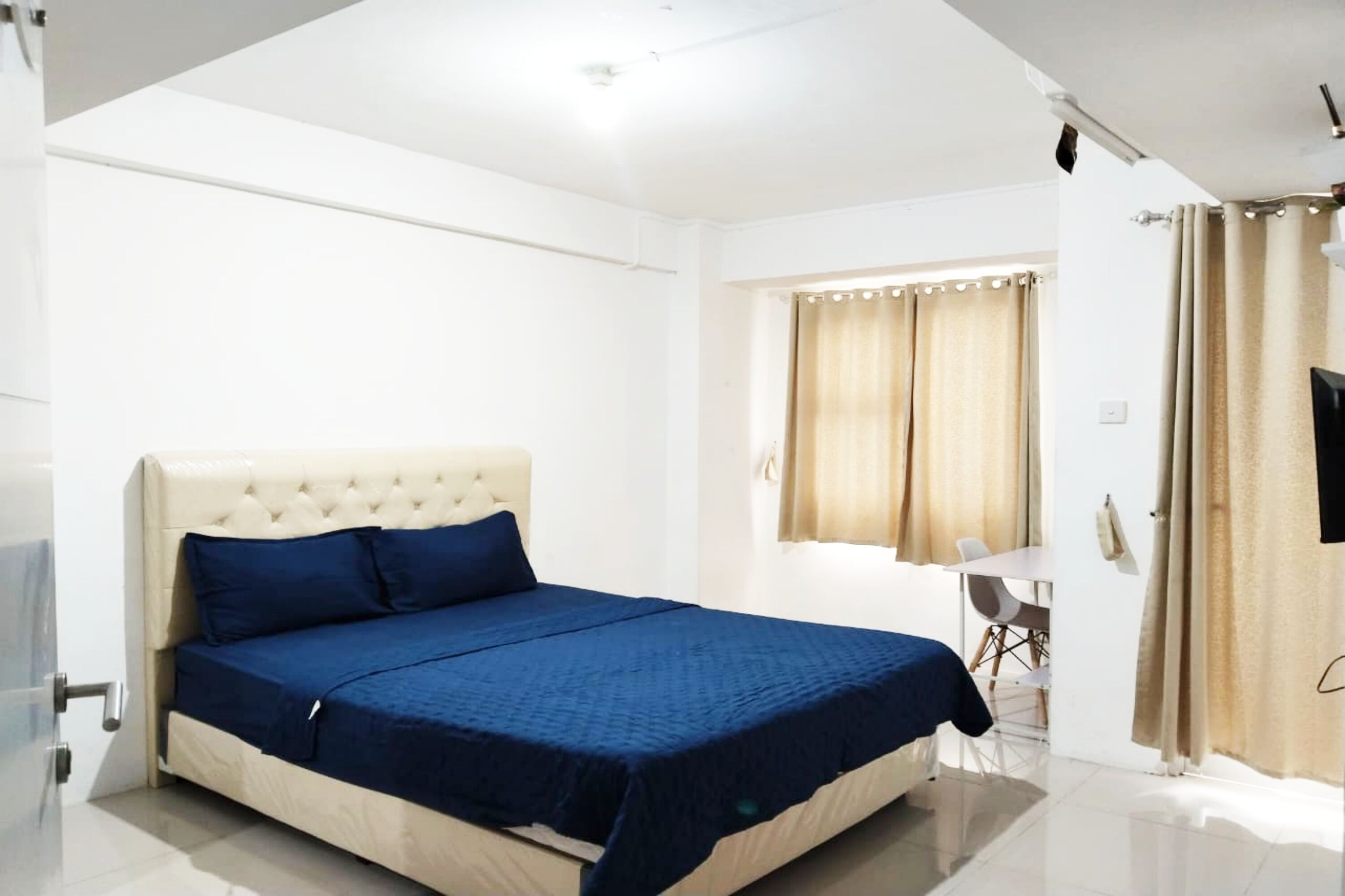 Een slaapkamer met een groot bed, een bureau en een stoel.