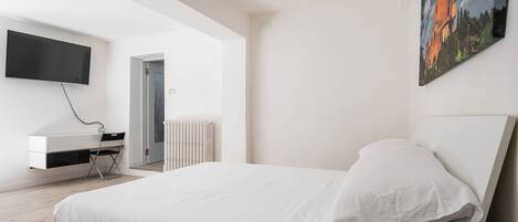 Un dormitorio moderno con una cama, un televisor montado en la pared y un cuadro.