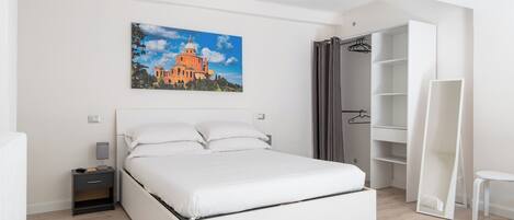 A bedroom with a bed, a nightstand, a wardrobe, and a painting on the wall.