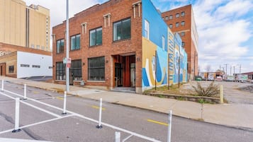 A multi-story building with a brick facade, large windows, and a colorful mural on the side.