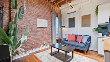 A living room with a brick wall, a blue sofa, a coffee table, and a potted plant.
