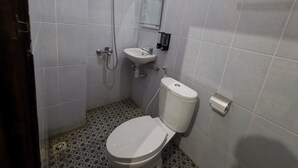 Un baño pequeño con inodoro, lavamanos y ducha.