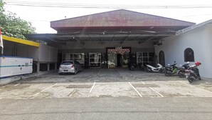 Un edificio con una entrada amplia, un coche estacionado frente a él y varias motocicletas aparcadas a un lado.