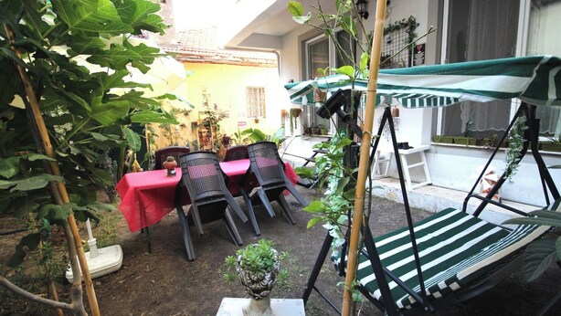 An outdoor patio with a table and chairs, a hanging chair, and a small plant on a table. - FETHİYE GARDEN HOUSE Apartment with private garden in the city center (Muğla)