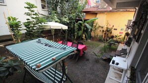A patio area with a striped table and chairs, a small table with a red tablecloth, and various plants. - FETHİYE GARDEN HOUSE Apartment with private garden in the city center (Muğla)