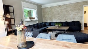 Een moderne woonkamer met een donkergrijze hoekbank, een houten salontafel en een decoratieve vaas op een bijzettafeltje.