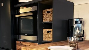 Een moderne keuken met een ingebouwde oven, een houten eettafel en een stoel.