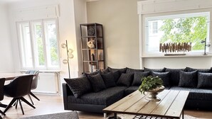 Een moderne woonkamer met een donkergrijze modulaire bank, een houten salontafel en een boekenplank.