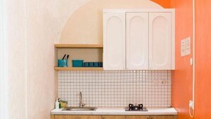 Cozinha com armários brancos, painel de azulejos e bancada de madeira. Há três banquetas na área do balcão.
