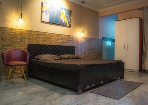 A bedroom with a bed, a chair, a wardrobe, and a painting on the wall. - Let'stay- Sector 63A Noida (Noida)