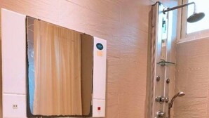 Ein Badezimmer mit einem weißen Waschbecken, einer Glasablage über dem Spiegel und einer Dusche mit Glastür.