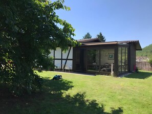 Une maison avec une grande porte vitrée, un jardin et un arbre.
