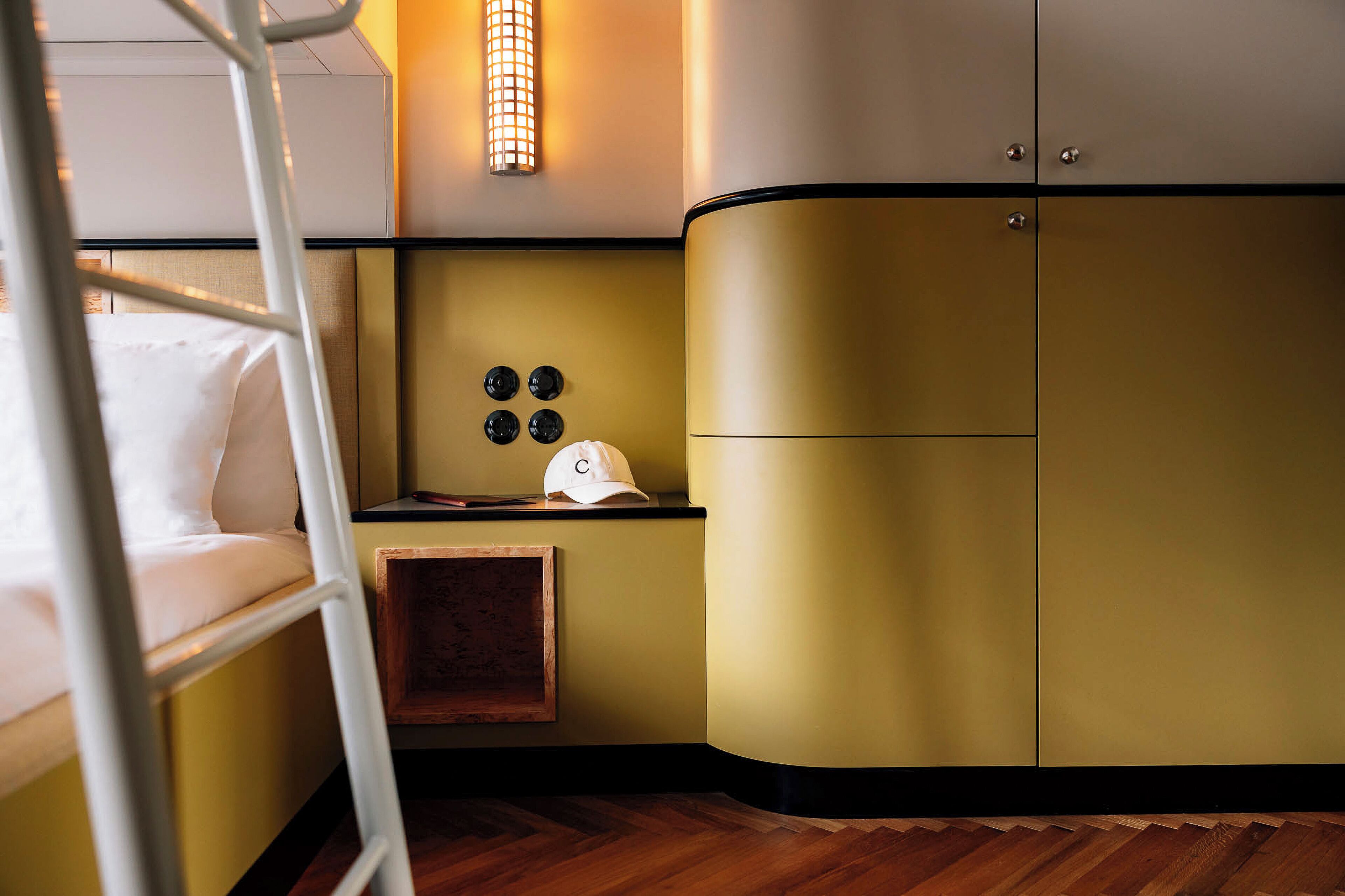 A bunk bed with a ladder, a bedside table with a cap, and a wall-mounted light fixture.