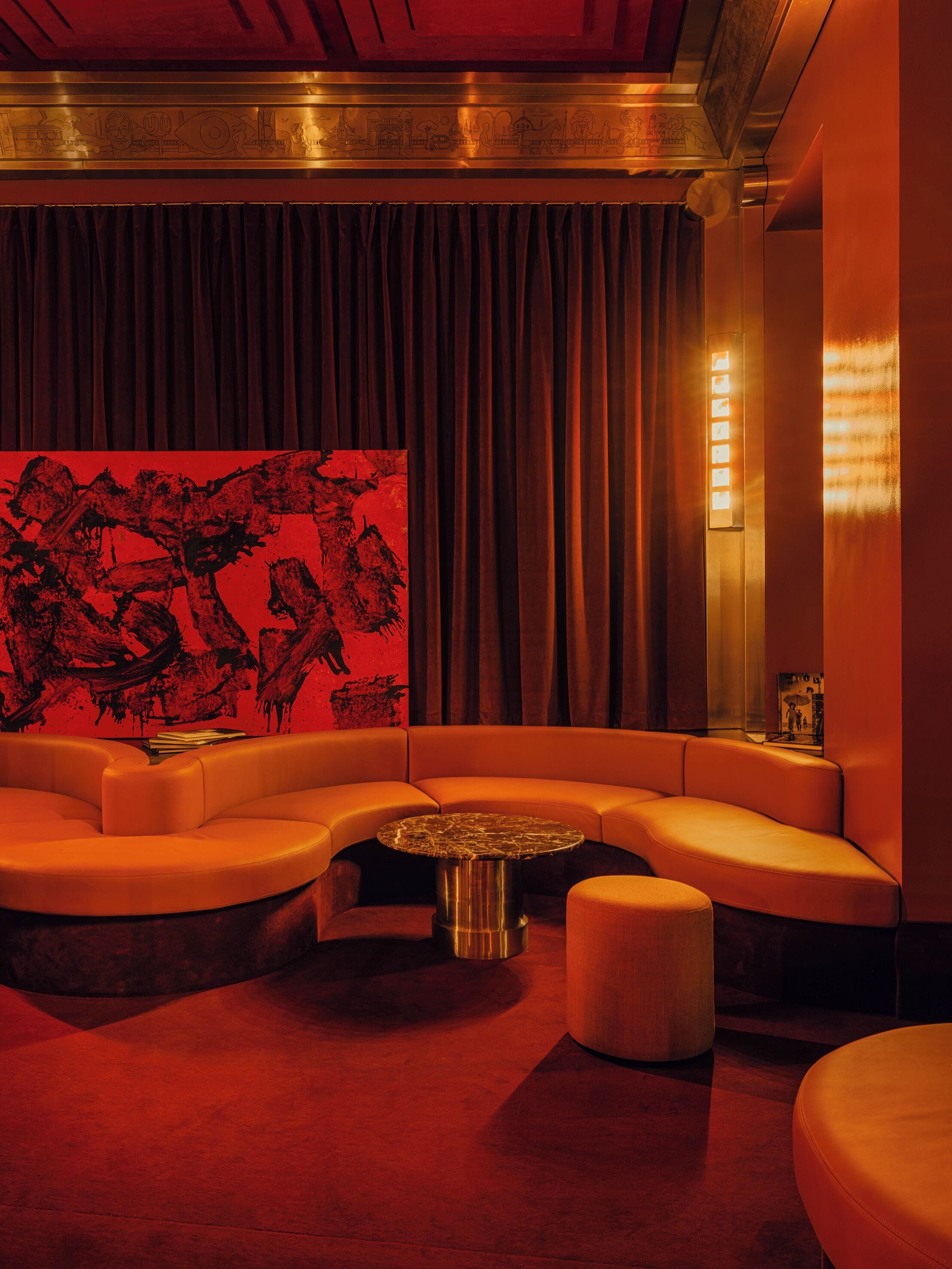 Un salón moderno con un sofá curvo, una mesa de centro redonda y una pared de acento roja.