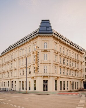 A large, historic building with a prominent entrance, multiple windows, and a distinctive corner design.