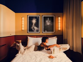 Una camera d'albergo con un letto, un comodino, una lampada e due quadri appesi al muro.