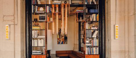 A library with bookshelves, a checkered floor, leather chairs, and a central seating area.