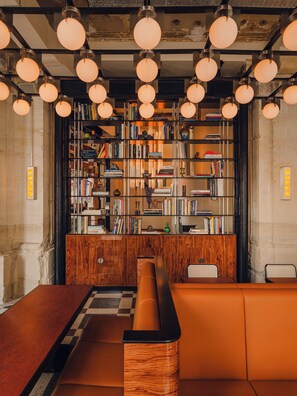 A library with bookshelves, a wooden desk, and a seating area.