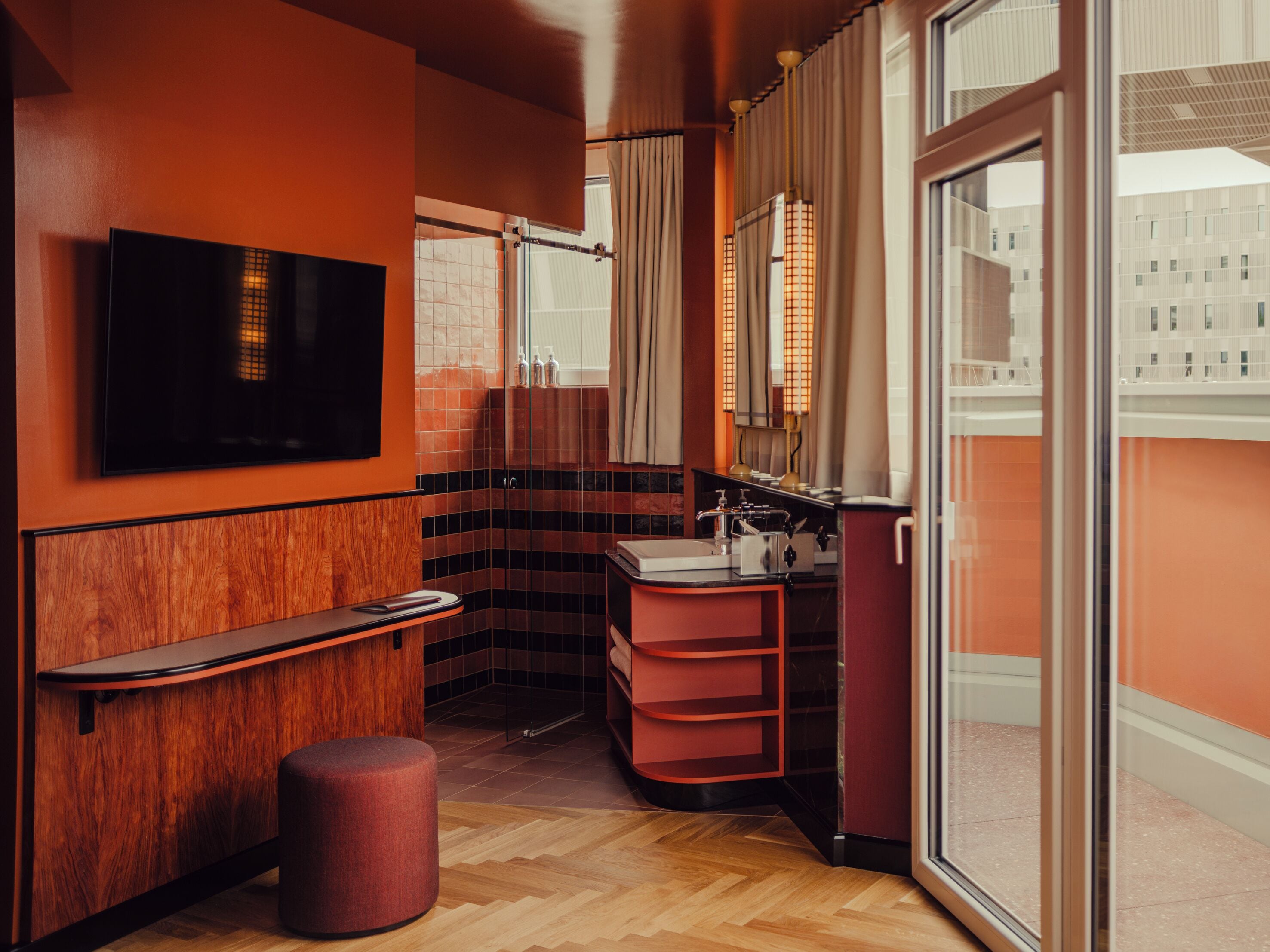 A modern bathroom with a wooden vanity, a mirror, a sink, and a television mounted on the wall.
