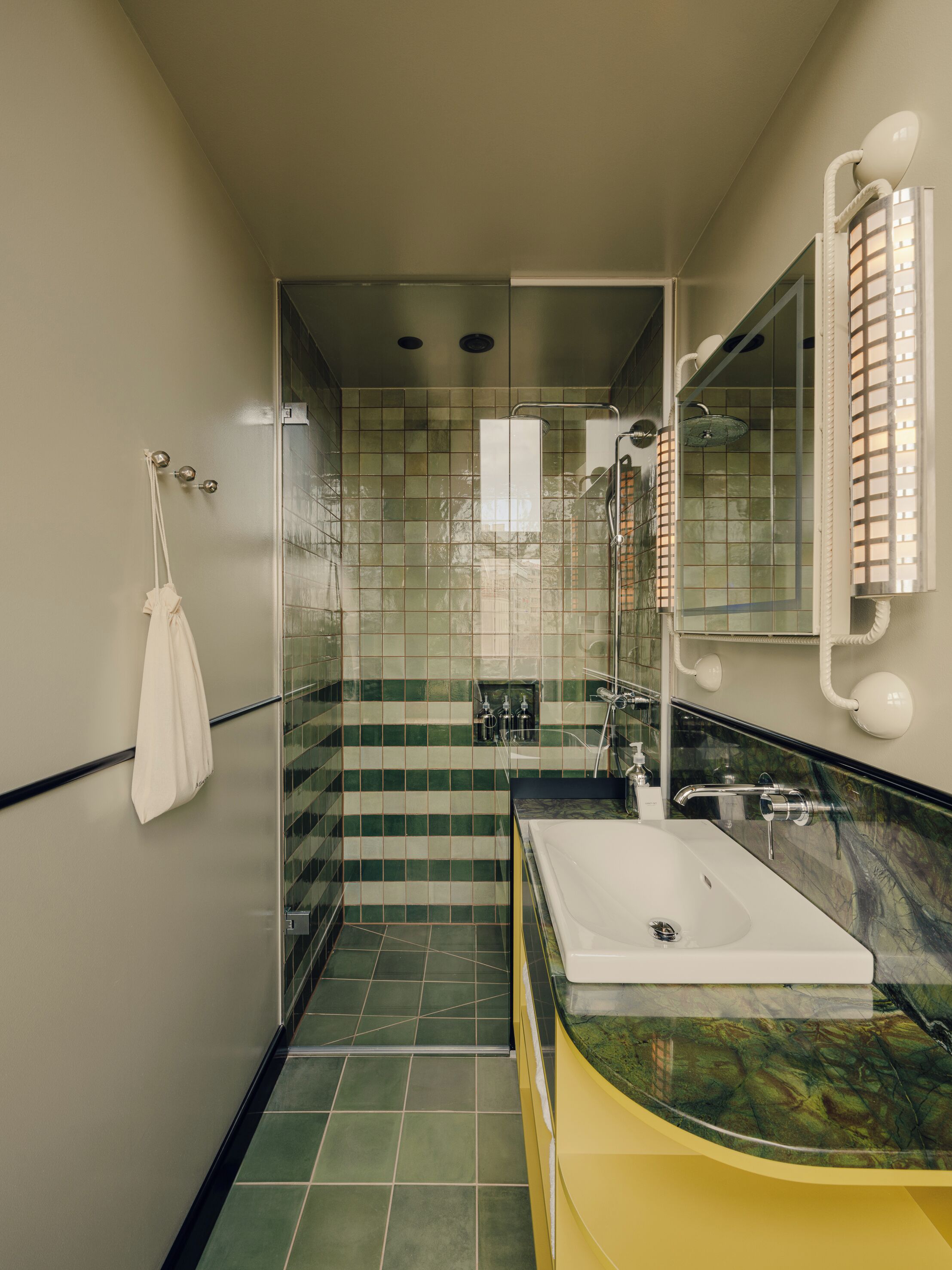 Ein Badezimmer mit Glasdusche, Waschbecken in Weiß und einem Spiegel mit Handtuchhalter.