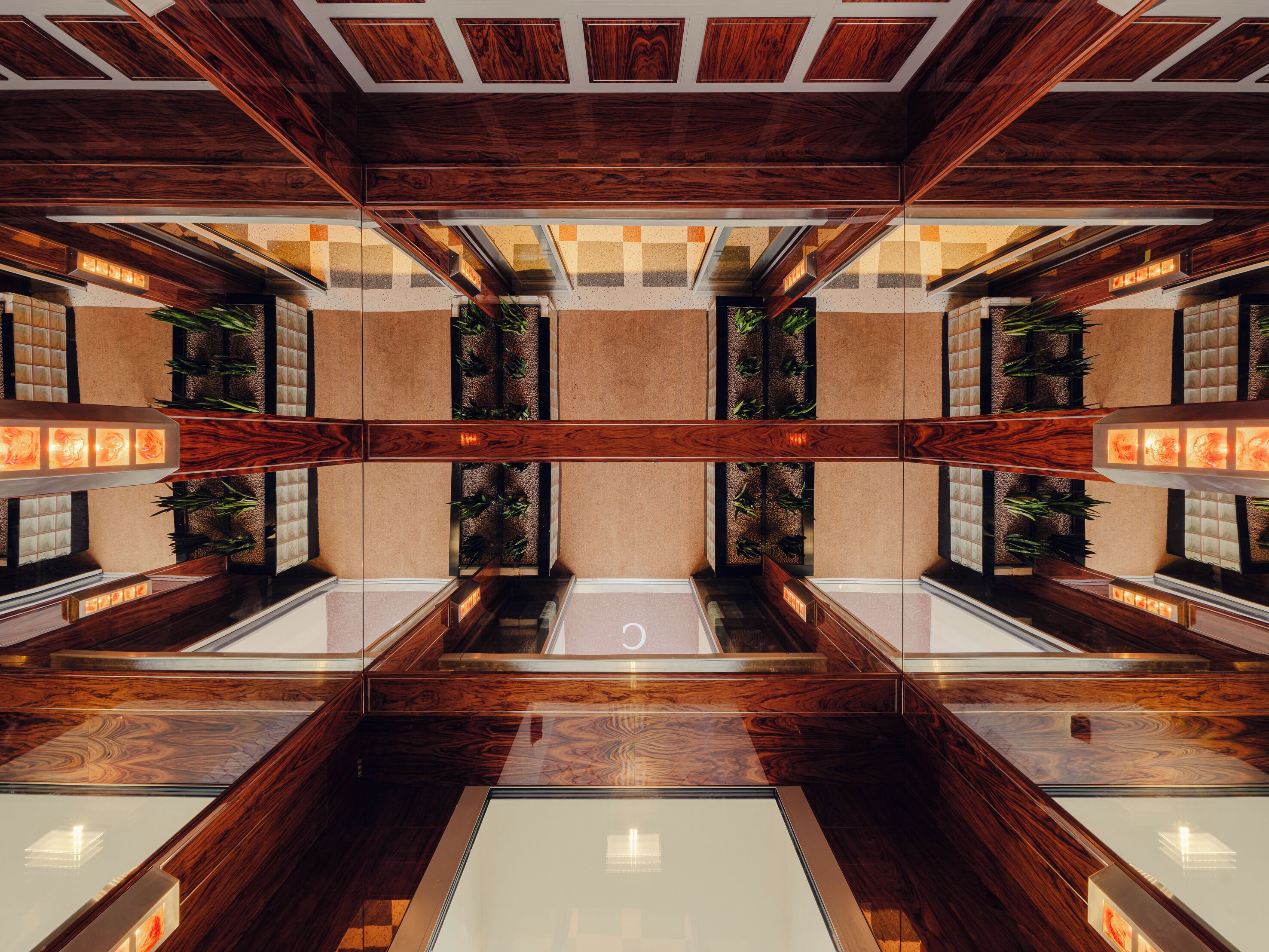 A modern interior with wooden paneling, reflective surfaces, and vertical plant installations.