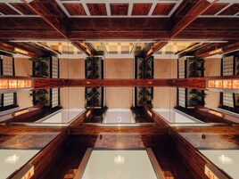 Um interior moderno com lambris de madeira, superfícies refletoras e jardins verticais.