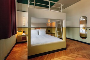 Camera con un letto a castello, una scala, un comodino, una lampada e uno specchio.